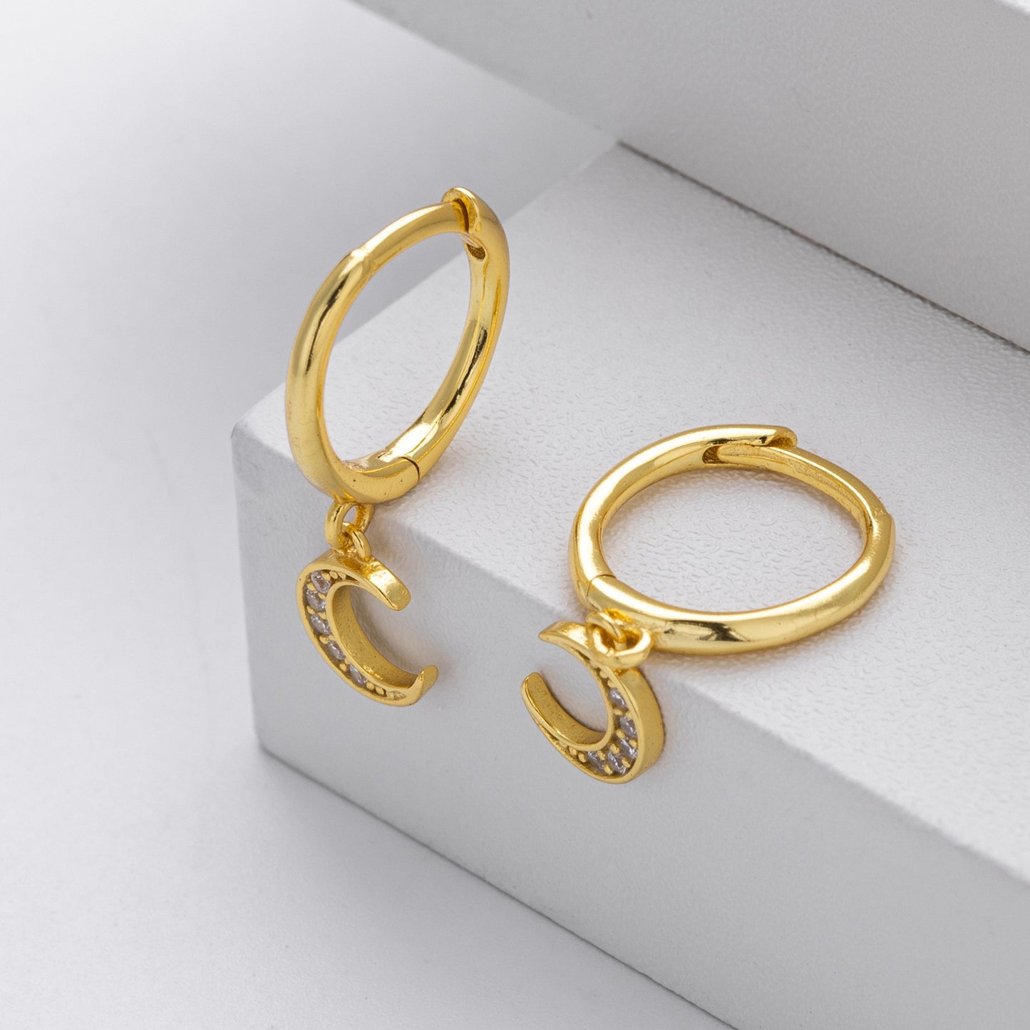 Close-up of gold plated crescent moon cz drop hoop earrings