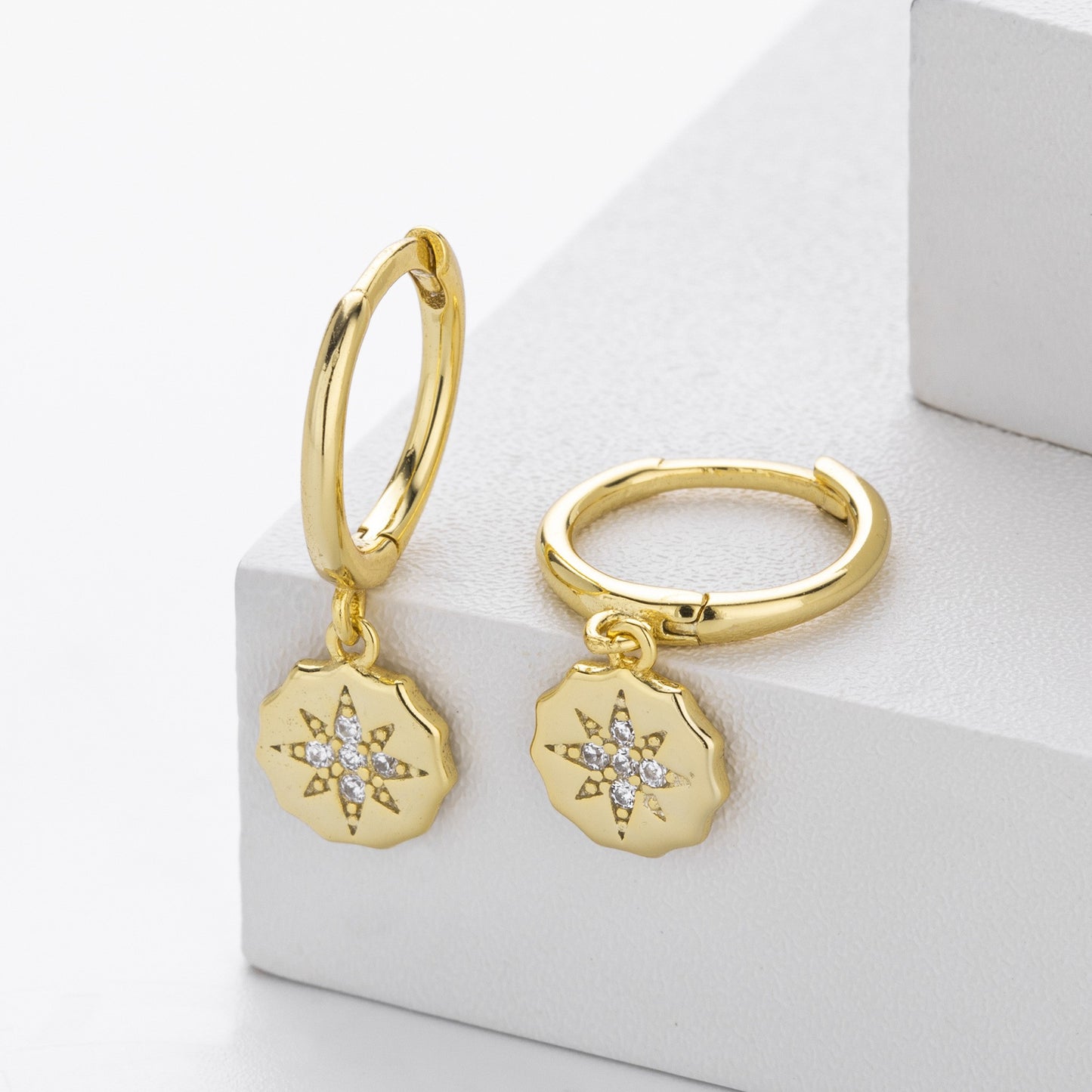 Close-up of gold plated starburst cz drop hoop earrings