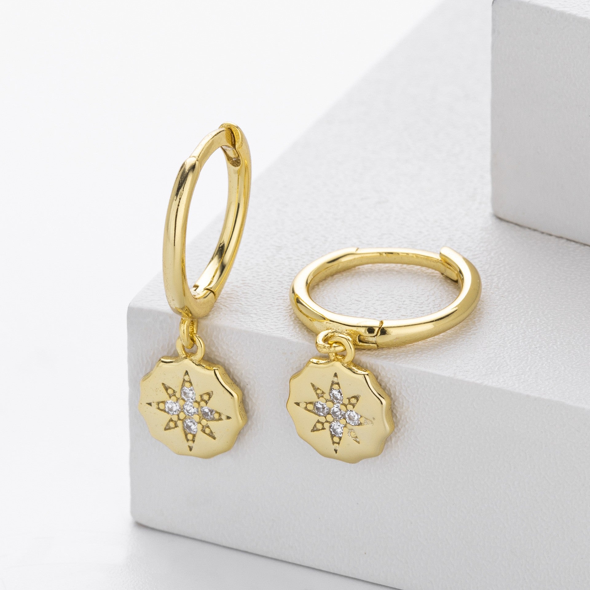 Close-up of gold plated starburst cz drop hoop earrings