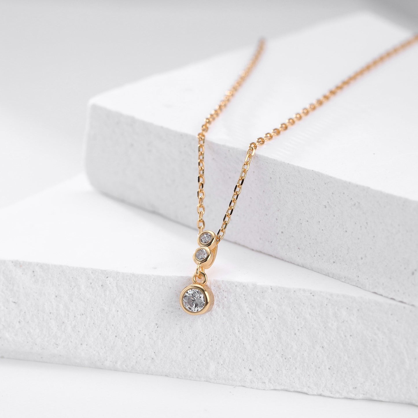 Close-up of gold plated three-tiered round cz drop necklace