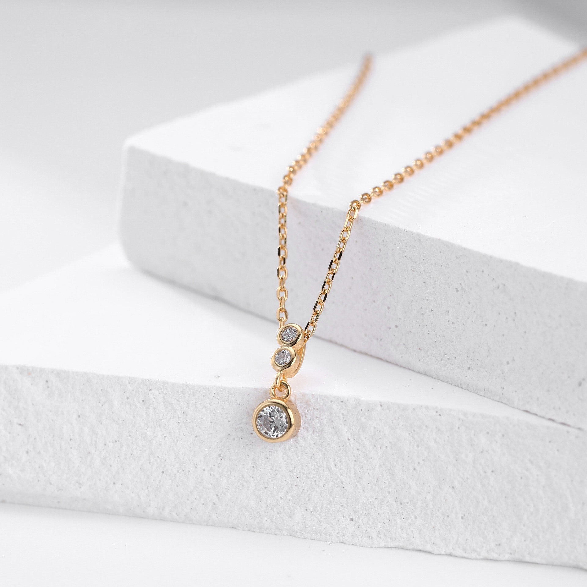 Close-up of gold plated three-tiered round cz drop necklace