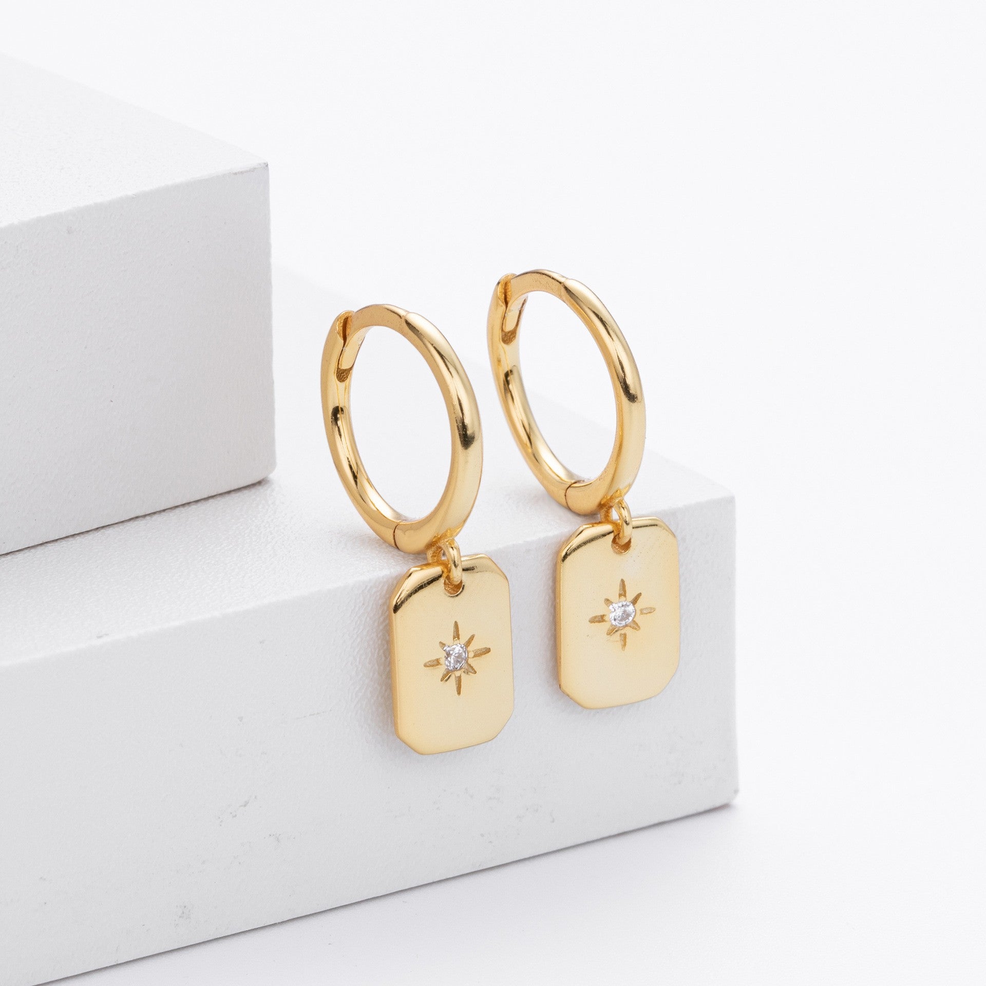Gold plated starburst tag drop hoop earrings close-up